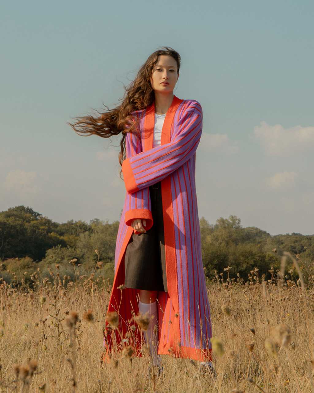 Women wearing a strpied long cardigan in orange and lilac in the park 